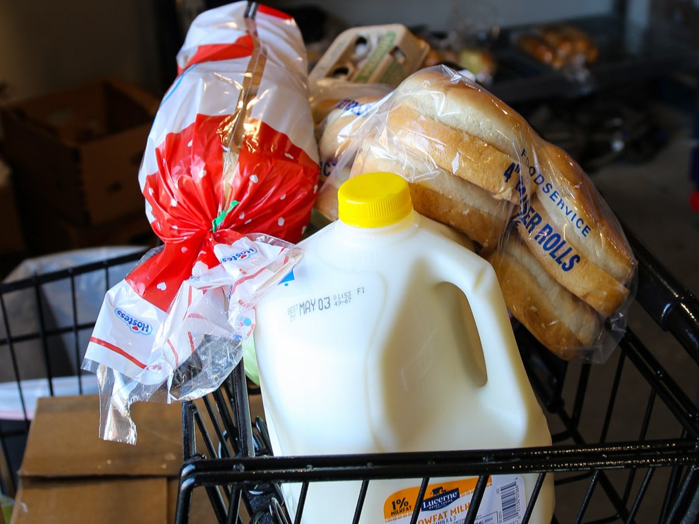 close up of milk and bread in shopping cart at food pantry