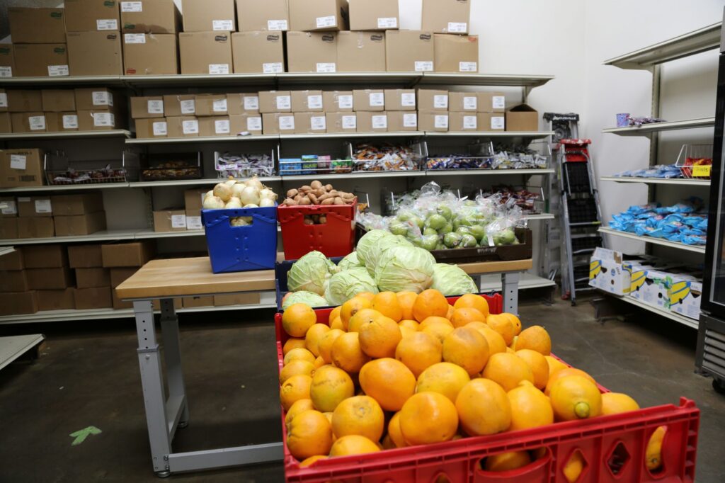 oranges and cabbages with onions, potatoes and pears in the background of a food pantry