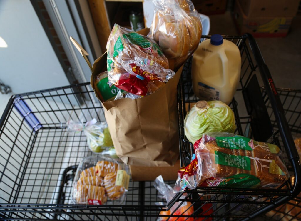 shopping cart filled with bread milk vegetables at food bank