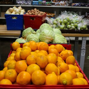 oranges and cabbages with onions, potatoes and pears in the background of a food pantry