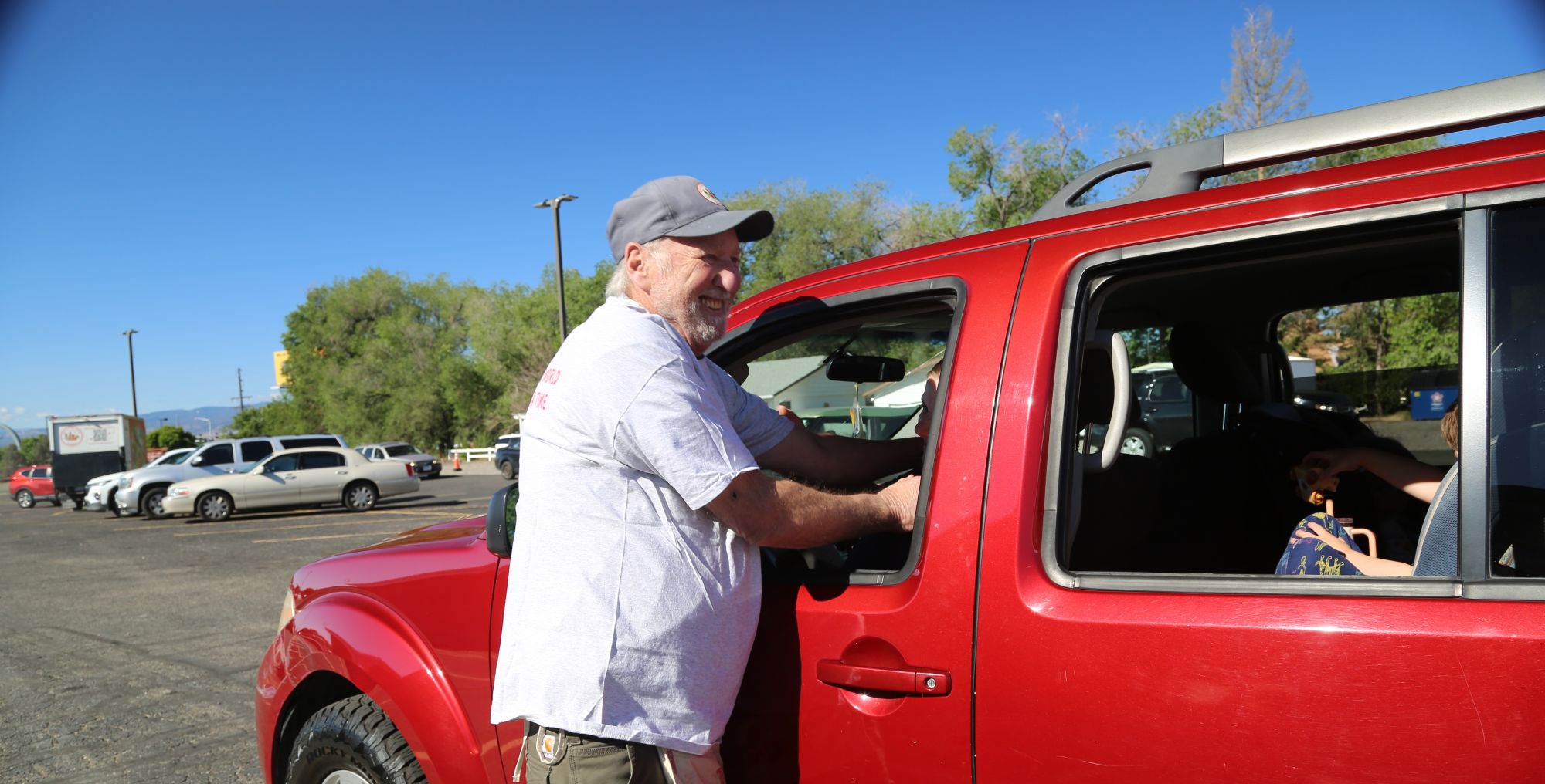 man laughing with customer by red car