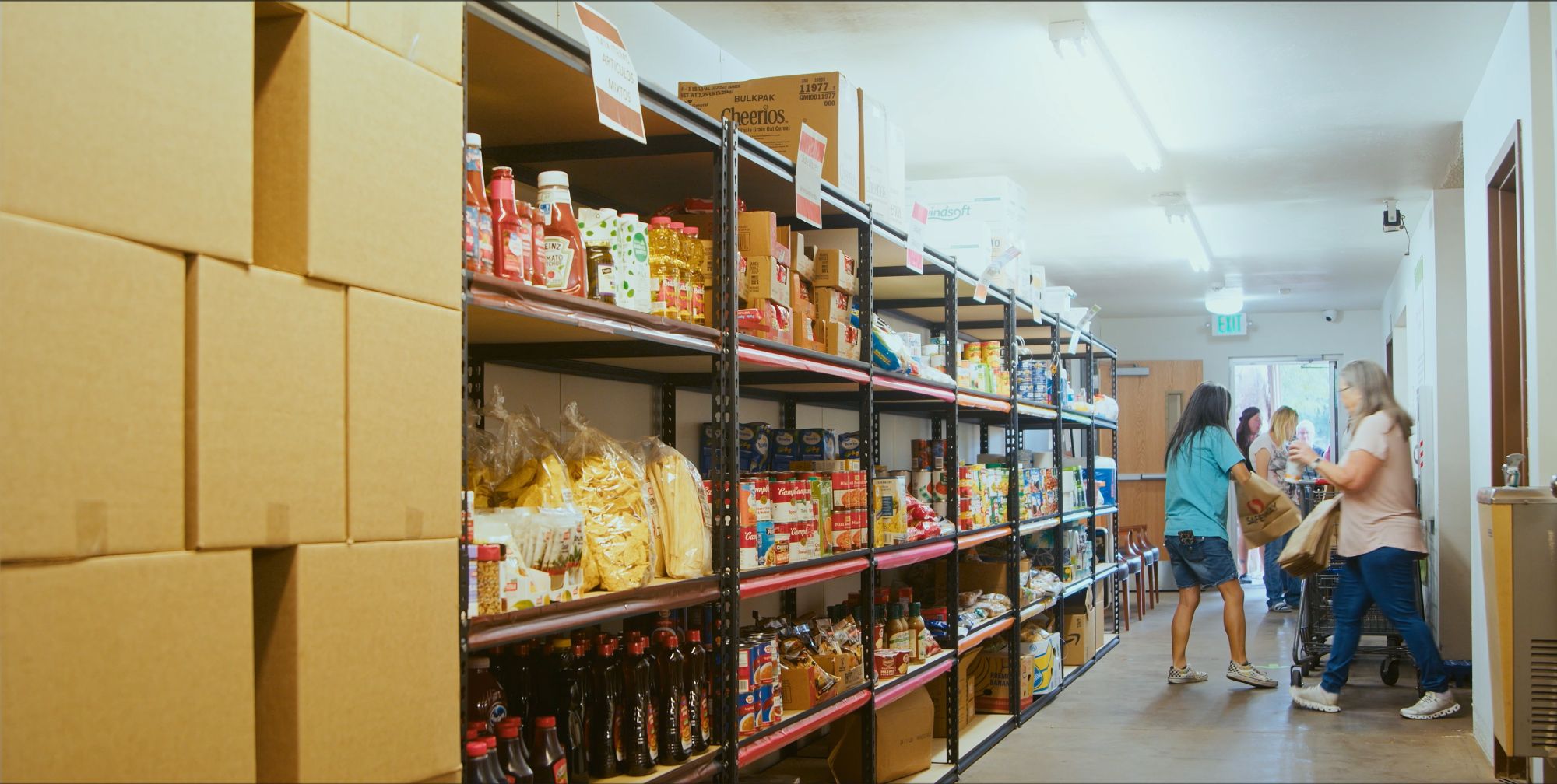 workers at food pantry in front of shelves of canned goods